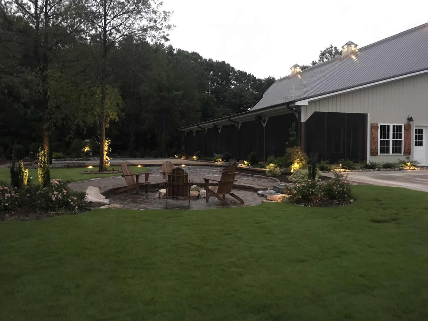 Outdoor lighting design for a stone fire pit area with chairs.