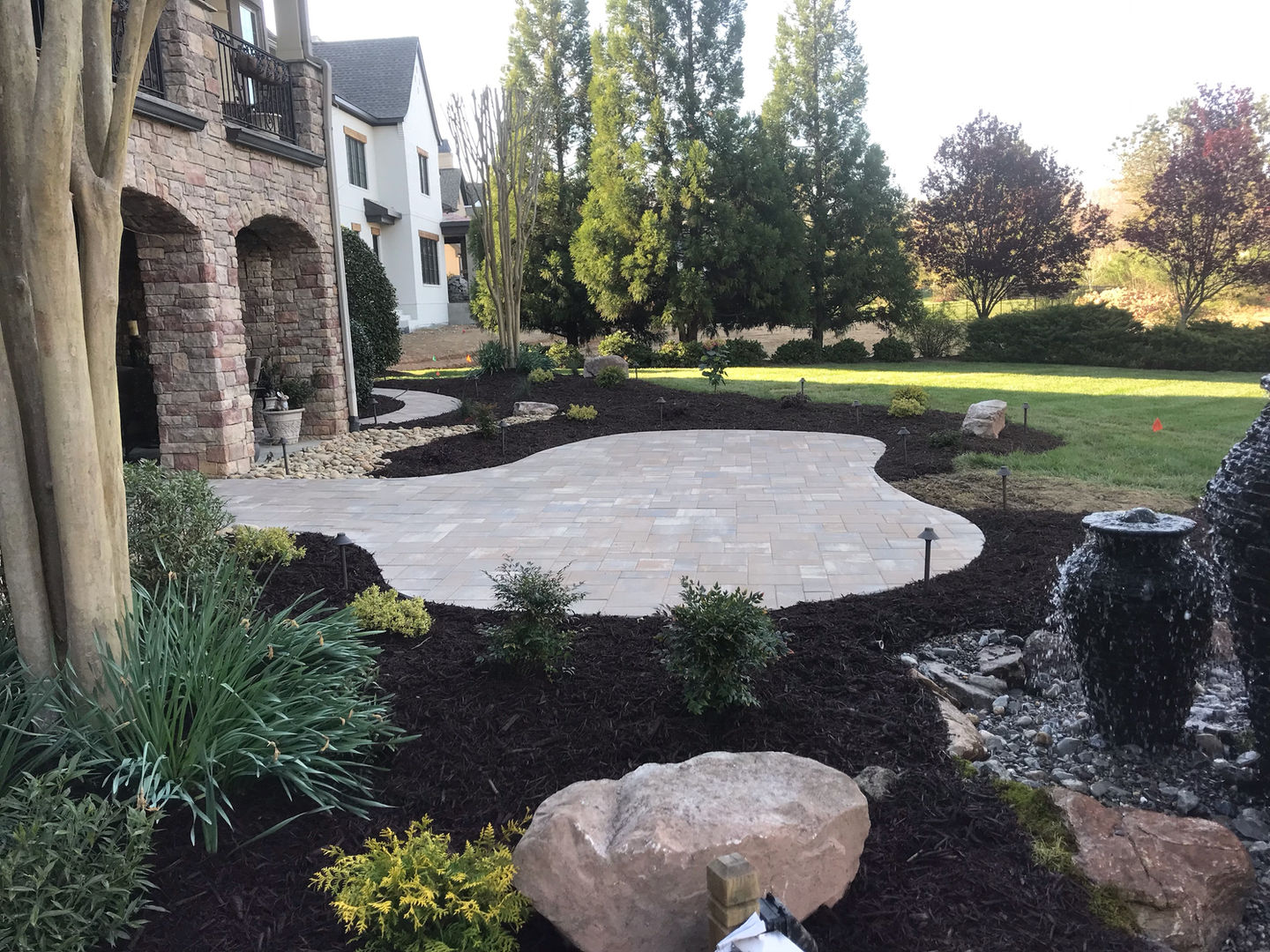 Curved stone patio with landscaping and water feature