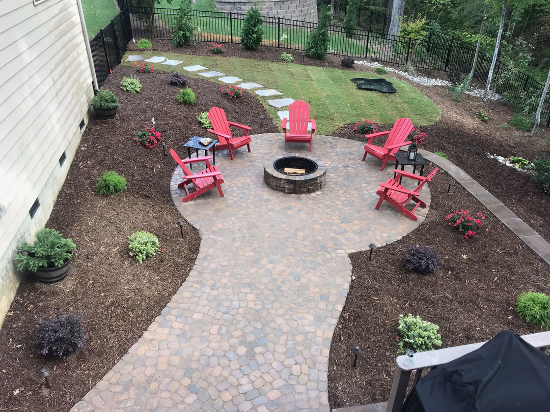 Unique circular patio design with fire pit and red chairs