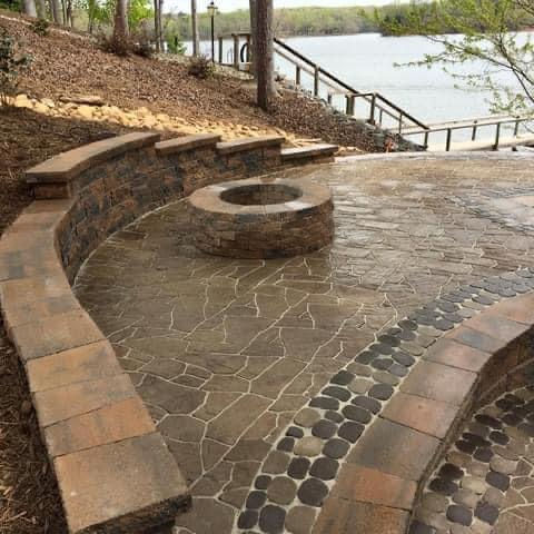 Large patio with stone fire pit and lake view.