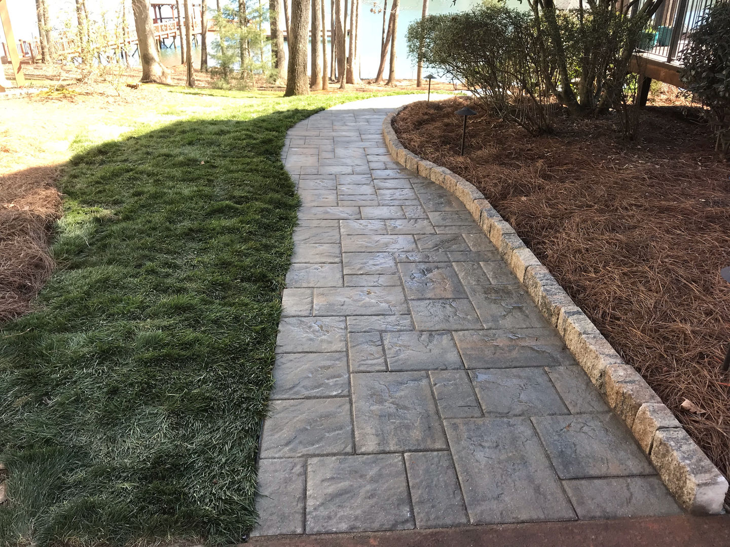 Curved stone paver walkway through a woodsy garden