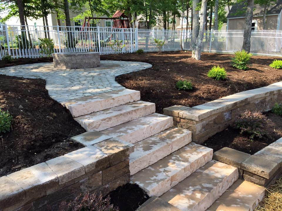 Stone stairway leads to a landscaped backyard patio area.