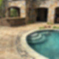 Outdoor stone patio with pool and built-in kitchen area