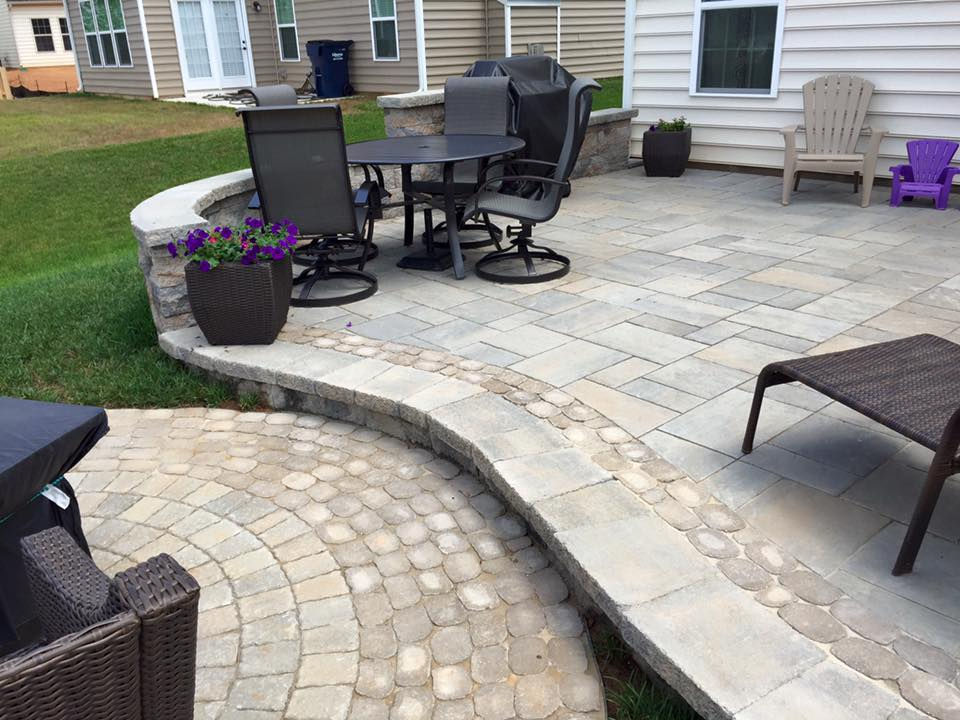 Stone patio with curved retaining wall and dining set.