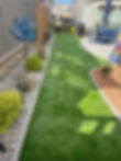 Small backyard with artificial turf path and patio area.